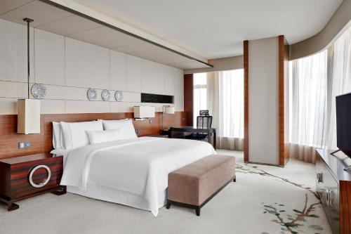 广州广州广交会威斯汀酒店的卧室配有一张白色大床和电视。