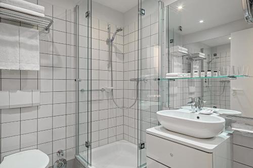 汉诺威汉诺威佩里坎喜来登酒店的一间带玻璃淋浴和水槽的浴室