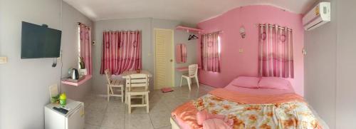 北碧Ban Suan Lung Rin的粉红色的卧室配有一张床、一张桌子和椅子