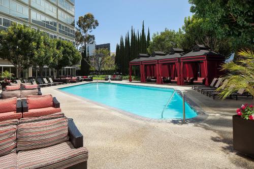 洛杉矶Sheraton Gateway Los Angeles Hotel的一座带躺椅的游泳池位于大楼旁