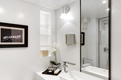 洛杉矶喜来登环球酒店的白色的浴室设有水槽和淋浴。