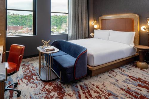 匹兹堡The Industrialist Hotel, Pittsburgh, Autograph Collection的配有一张床和一把椅子的酒店客房