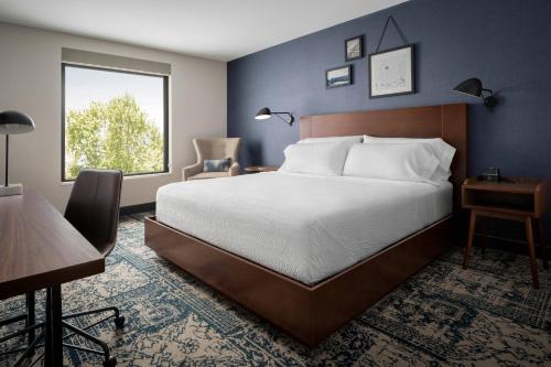 默特尔比奇Four Points by Sheraton Myrtle Beach的一间卧室配有一张床、一张书桌和一个窗户。