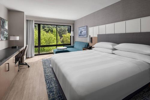 普莱森顿普莱森顿万豪酒店 的卧室配有一张白色大床和一张蓝色椅子