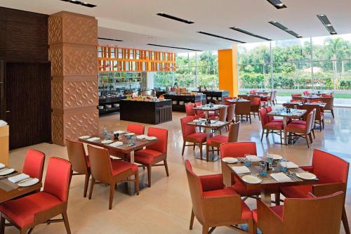 勒克瑙勒克瑙费尔菲尔德客栈酒店的餐厅设有木桌和红色椅子