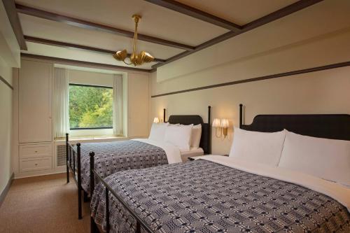 普莱西德湖Grand Adirondack Hotel, Lake Placid, a Tribute Portfolio Hotel的酒店客房设有两张床和窗户。