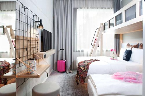 鲁斯特Moxy Rust的酒店客房带两张床和粉红色的行李箱