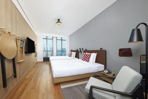 上海上海徐汇Moxy酒店的配有一张床和一把椅子的酒店客房