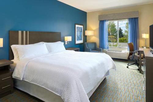 威利斯顿威利斯顿福朋喜来登酒店的酒店客房设有一张白色大床和一个窗户。