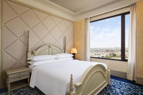 印多尔Sheraton Grand Palace Indore的卧室设有一张白色大床和大窗户