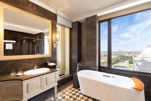 印多尔Sheraton Grand Palace Indore的带浴缸、水槽和窗户的浴室