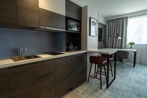 布拉尼亚克Residence Inn by Marriott Toulouse-Blagnac的厨房配有木制橱柜和一张带凳子的桌子