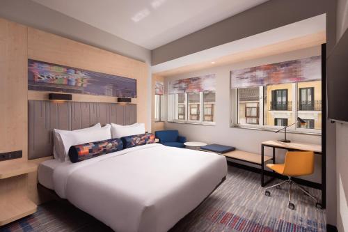 马德里Aloft Madrid Gran Via的酒店客房设有一张床、一张书桌和两个窗户。