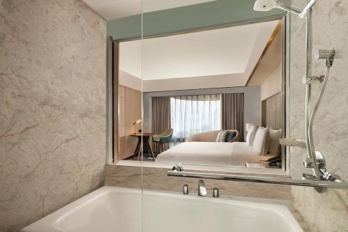 雅加达雅加达纱丽太平洋酒店的带浴缸的浴室和卧室