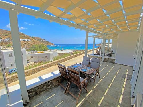 米克诺斯城1Path Wave Mykonos Super Paradise Beach House的一个带桌椅的庭院和大海