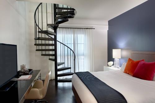 迈阿密Hotel Colonnade Coral Gables, Autograph Collection的卧室设有螺旋楼梯,位于床边