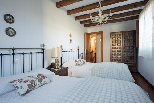 PeñacobaCasa Rural Martínez的一间卧室配有两张床和吊灯。