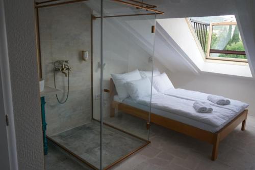 特雷比涅Hotel Restoran Humsko的卧室内的玻璃淋浴间,配有床
