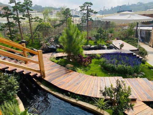大叻Dớt's Garden Homestay的一个带木制走道和池塘的花园
