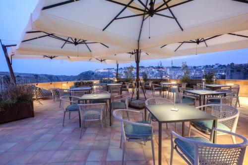 马泰拉Quarry Resort的一个带桌椅和遮阳伞的庭院