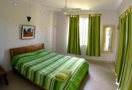 拉戈莱特Villas Hibiscus的一间卧室配有绿色的床和绿色窗帘