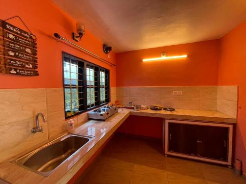 蒙纳Mountain cheers munnar的厨房设有橙色的墙壁、水槽和窗户