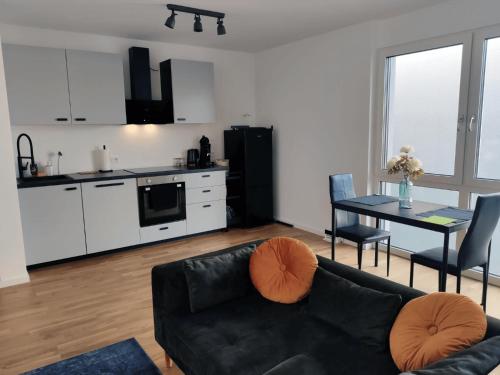 贝尔吉施格拉德巴赫Moderne Wohnung mit Loggia - Neubau 2023的一间带黑色沙发的客厅和一间厨房