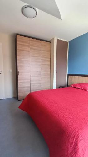 莱代塞尔Appartement Le Montagnard的一间卧室配有一张红色的床和木制橱柜。