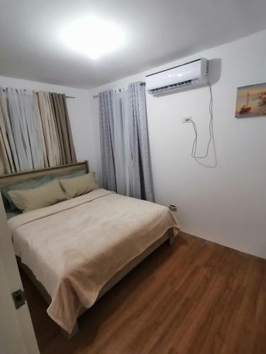 武端市CAMILA Homes Transient house /vacation house的卧室配有一张床,墙上配有空调