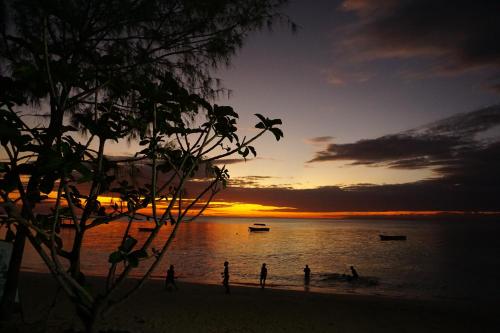 南威Cocolala Beach House的一群人,在日落时站在海滩上