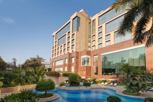 新德里Sheraton New Delhi Hotel的建筑前的一座带游泳池的建筑