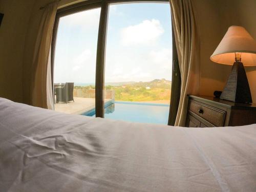 罗阿坦Relax Enjoy Upscale Villa Pristine Bay的一间卧室设有一张床和一个享有游泳池景致的窗户。