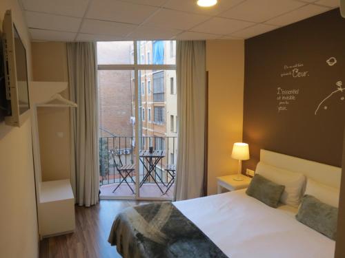 巴塞罗那佩蒂特普里塞普旅馆的一间卧室设有一张床和一个阳台的窗户。