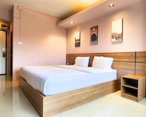 南邦AIRBEST Gemtree Lampang Hotel的一间卧室配有一张大床和木制床头板