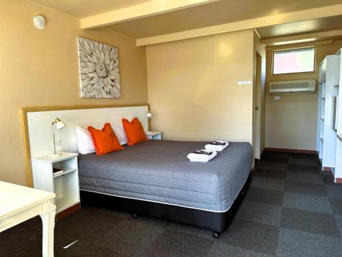 WarialdaSunflower Motel的一间卧室配有带橙色枕头的床