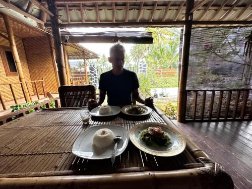 特特巴图Mysha Guest House-Lombok的坐在餐桌上,有食物盘的人