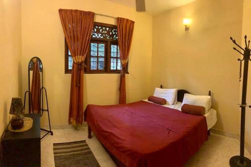 康提Dili's Home Stay的一间卧室设有红色的床和窗户。