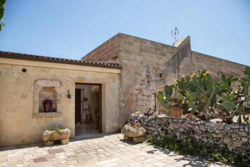 佩斯科勒海滨Antica Masseria Ficazzana - Tenuta的一座古老的石头房子,有门和仙人掌
