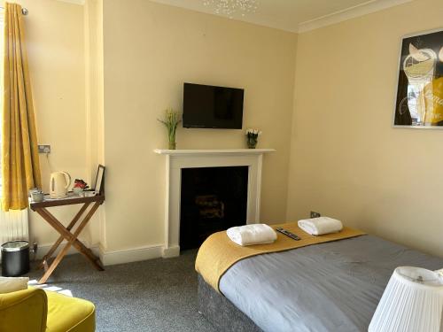 约克白合斯宾馆的一间卧室配有一张床和一个壁炉及电视