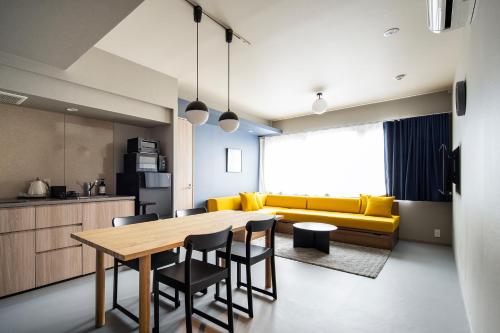 东京Section L Tsukiji的厨房以及带桌子和黄色沙发的用餐室。