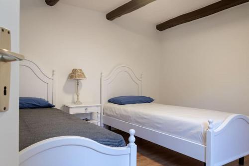 布里萨戈Rustico Porta的卧室设有2张床和白色的墙壁。