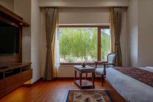 列城Hotel Gyalpo Residency - A Mountain View Luxury Hotel in Leh的一间卧室设有一张床、一台电视和一个窗口。