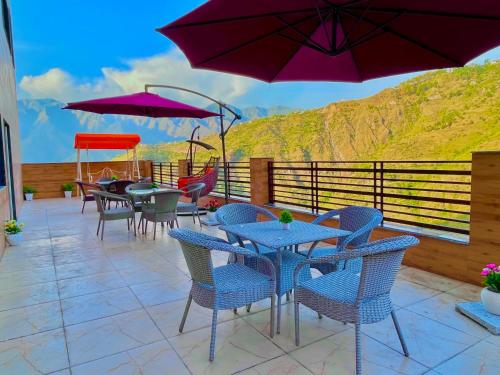 穆索里Doon Valley Resort, Mussoorie的一个带桌椅和紫色遮阳伞的庭院