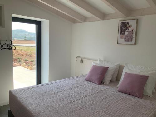 Quinta da Ema的一间卧室配有一张带紫色枕头的床和窗户。