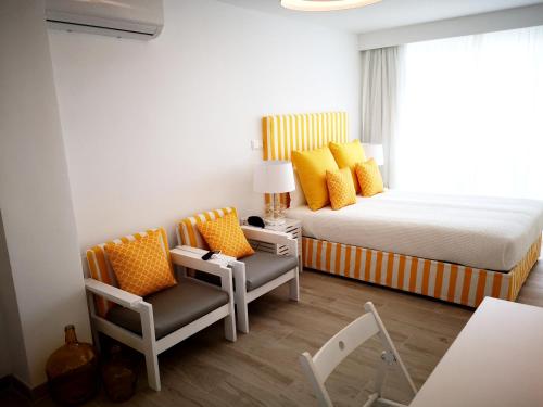 米尔芳提斯城Hotel HS Milfontes Beach - Duna Parque Group的一间卧室配有一张床、两把椅子和一个窗户