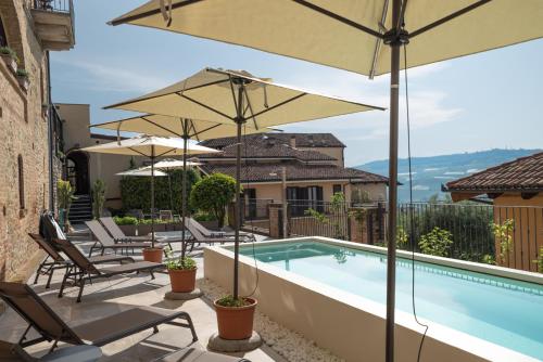 卡斯蒂廖内法莱托Le Torri - Castiglione Falletto的房屋旁的游泳池配有遮阳伞和椅子