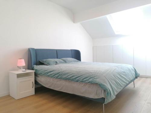 ChâteletLa Maison Heureuse的一间卧室配有一张蓝色的床和一个带灯的床头柜。
