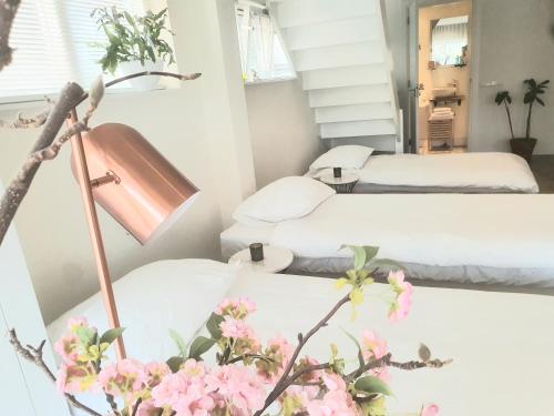 福伦丹Luxury loft at lake Volendam 20 min. from Amsterdam CS的一间设有两张床、一盏灯和鲜花的房间