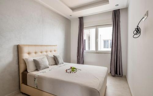 杰迪代Appartement 3 CHAMBRES ensoleillé à 5 min de la plage El Jadida的一间卧室配有一张白色大床,床上有鲜花