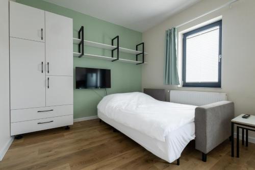 罗兹Brzeska 22的卧室配有白色的床和电视。